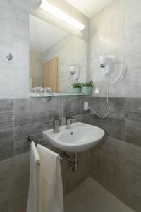 ein Badezimmer mit einem Waschbecken, einem Spiegel und Handtüchern in der Unterkunft Solid Gold - OPENING AUGUST 2024 in Malacky