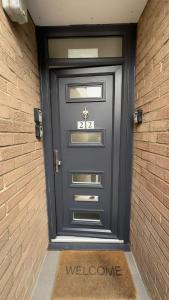 czarne drzwi z napisem powitalnym przed nimi w obiekcie 15 min to Central London Guest Suites 22 w Londynie