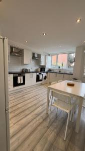 a kitchen with a white table and chairs in it at 15 min to Central London Guest Suites 22 in London