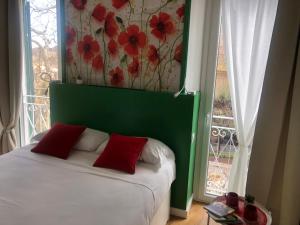 Bett mit roten Kissen in einem Zimmer mit Fenster in der Unterkunft DIMOR'A' ROOMS in Pitigliano
