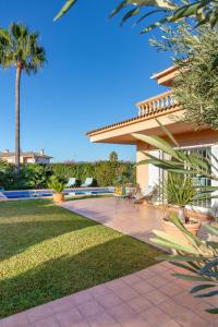 a house with a patio with chairs and a palm tree at Villa Palmera in Palma de Mallorca