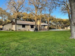 a house in a field with a yard with trees at Hill Country House & Pool - Fiesta Texas Sea World in San Antonio