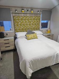 a bedroom with a large white bed with a yellow headboard at Loch View 30 in Stranraer