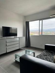 uma sala de estar com uma televisão, um sofá e uma mesa de vidro em Mendoza desde lo alto em Mendoza