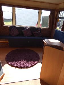 a living room with a blue couch and a rug at Sunrise Caravan in Dymchurch