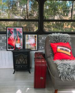 a living room with a couch and a suitcase at Ônibus Retrô - Domingos Martins/ES in Domingos Martins