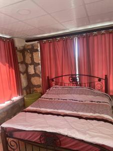 uma cama num quarto com cortinas vermelhas em Heritige Inn Jordan em Ad Dimnah