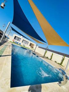 a large swimming pool with a large umbrella over it at Heritige Inn Jordan in Ad Dimnah