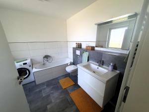 a bathroom with a sink and a tub and a toilet at geräumige, moderne Ferienwohnung mit PKW- und Fahrradstellplatz - FeWo Nordland in Schwerin