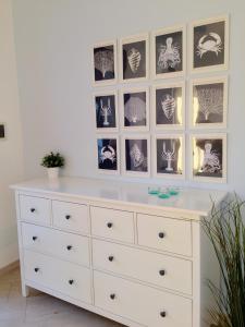 a white dresser with pictures on the wall at Casa Oltremare UnmarediBlu in San Vito lo Capo