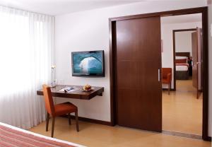 a room with a desk and a door with a table at Hotel Estelar El Cable in Manizales