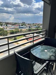 balcone con tavolo, sedie e vista su un treno di DMN City Junction Apartment a Windhoek