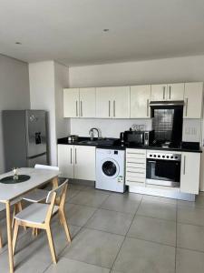 a kitchen with white cabinets and a table and a sink at DMN City Junction Apartment in Windhoek