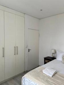 DMN City Junction Apartment في ويندهوك: غرفة نوم بيضاء مع دواليب بيضاء وسرير