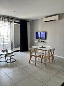 un soggiorno con tavolo, sedie e TV di DMN City Junction Apartment a Windhoek