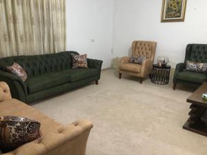 a living room with a green couch and two chairs at Family House in Al Azraq ash Shamālī