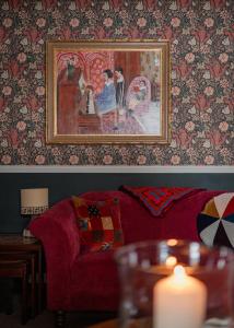 a living room with a red couch and a painting on the wall at Luxury 3 Bedroom Cottage - Sleeps 6 in Tomintoul