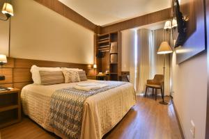 Habitación de hotel con cama y silla en Pousada Stillo Gramado Exclusive, en Gramado