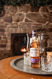 a bottle of bourbon sitting on a table with glasses at Luxury 3 Bedroom Cottage - Sleeps 6 in Tomintoul