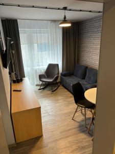 een woonkamer met een bank, stoelen en een tafel bij Guest Apartments Orłowo in Gdynia