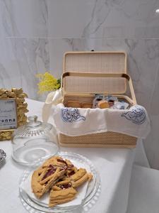 a table with a plate of cookies and a picnic basket at Centro storico, Centralissimo LUXURY SMERALDO SUITE Doccia Idromassaggio , cesto con piccola colazione in Ravenna