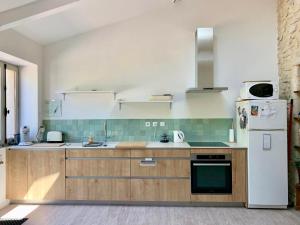 a kitchen with wooden cabinets and a white refrigerator at Charme de la pierre, pour cette maison de vacances in Grane