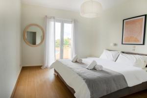1 dormitorio blanco con 1 cama grande y espejo en Thea Studios, en Kassiopi