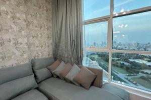 a couch in a living room with a large window at TOP VIEW Luxury 1-bedroom amazing view in Ajman 
