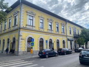 a yellow building with cars parked in front of it at City Center Apartman in Satu Mare