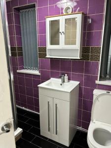 een paars betegelde badkamer met een wastafel en een toilet bij Stunning 2 bed rear flat Manchester in Manchester