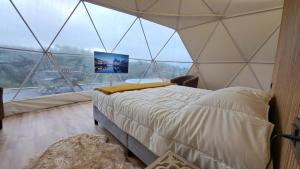 um quarto com uma cama numa tenda com uma grande janela em CasasEcoNatura 