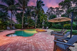 einen Pool mit 2 Stühlen und einem Sonnenschirm in der Unterkunft Nautical Escape! Private pool home with a tropical backyard oasis! in Bradenton