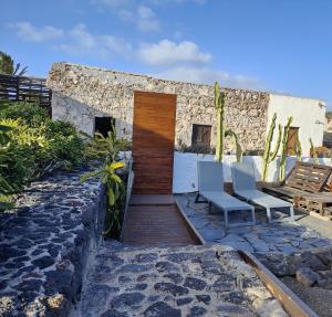 a patio with two chairs and a wooden door at Las Casitas Masdache in Tías