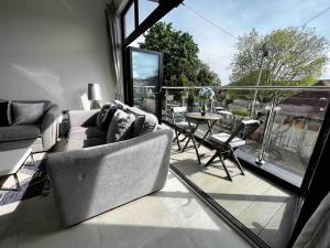 ein Wohnzimmer mit einem Sofa und einem Tisch auf dem Balkon in der Unterkunft Ultra modern apartment near Southsea seafront in Portsmouth