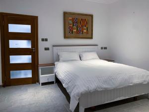 - une chambre avec un lit blanc et une porte en bois dans l'établissement Cony’s Guest House, à Kwabenyan