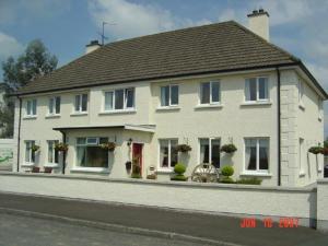 uma grande casa branca ao lado de uma rua em Drumcoo Guest House em Enniskillen
