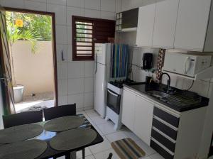a kitchen with white appliances and a table and chairs at Rota do Sol Flat in Natal