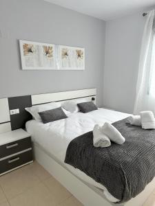 a white bed with two white towels on it at Luxurious, Newly-Renovated Large 2-Bedroom Condo by the Beach in Benidorm