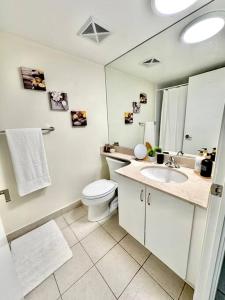 La salle de bains blanche est pourvue de toilettes et d'un lavabo. dans l'établissement Lake View Apartment w/Parking!, à Toronto