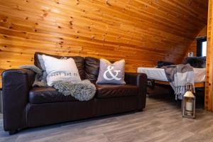 un divano in pelle marrone in una camera con pareti in legno di The Arns Glamping Pods a Bridge of Allan