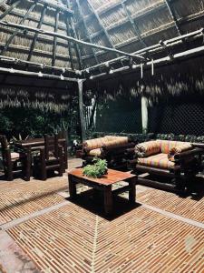 a patio with couches and a table and a roof at Island-style lodging & beach club in Tierra Bomba