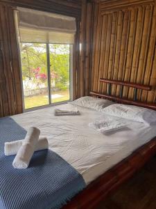 a bed with two towels on it with a window at Island-style lodging & beach club in Tierra Bomba