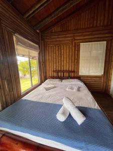 a bed in a wooden room with two towels on it at Island-style lodging & beach club in Tierra Bomba