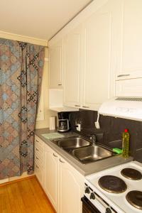 una cocina con armarios blancos y fregadero en 2-Bedroom Apartment in Heart of City Center en Turku