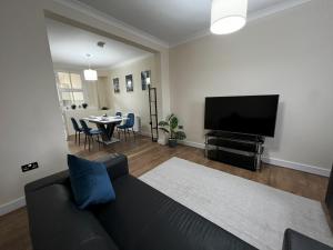 een woonkamer met een bank, een tv en een tafel bij Two Bedroom Holiday Home in Merton