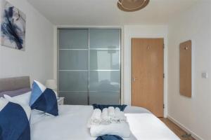 a bedroom with a large white bed with blue pillows at Luxury Milton Keynes Apartment at The Prevé in Milton Keynes