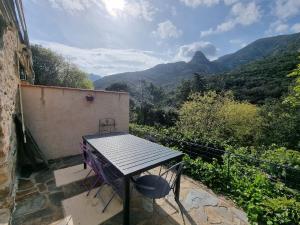 einen Tisch und einen Stuhl auf einem Balkon mit Bergblick in der Unterkunft la bergerie in Sorède