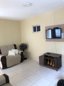 a living room with a couch and a tv on the wall at Casa Costa do Mar - Pé na areia em Maragogi in Maragogi