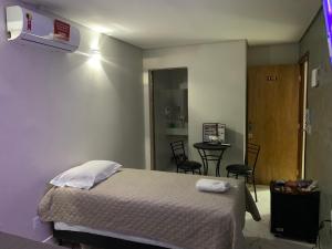 1 dormitorio con 1 cama y 1 mesa con sillas en Hotel Oásis en Brasilia