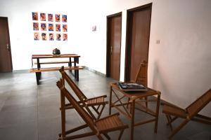 Zimmer mit 2 Stühlen, einem Tisch und 2 Tischen in der Unterkunft Les Amazones Rouges Chambre Jaune in Ouidah